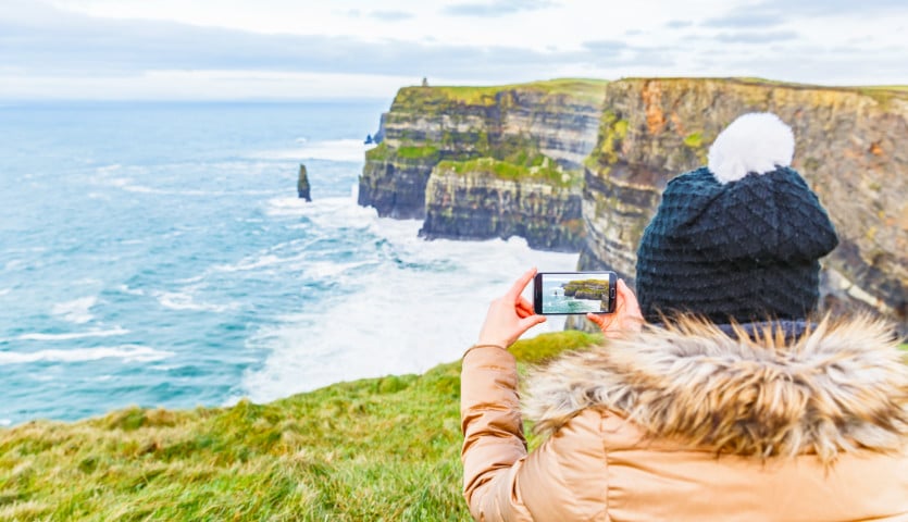 Woman taking a photo of the Cliffs of Moher