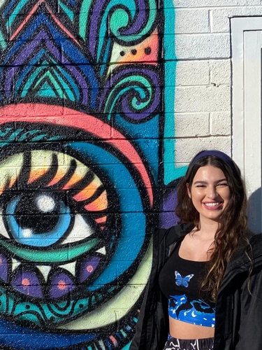 Isabelle Pavese with a colorful mural on her side at the Arts District