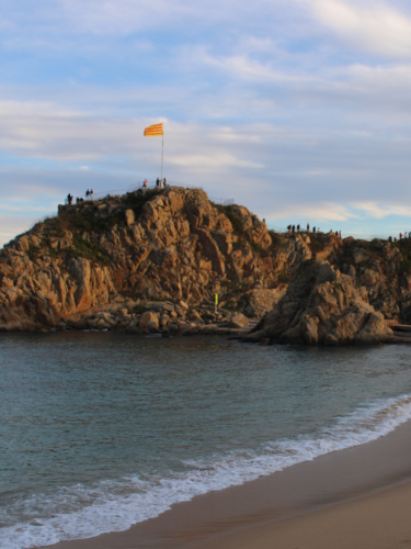 A flag on the peak of the island rock at dusk