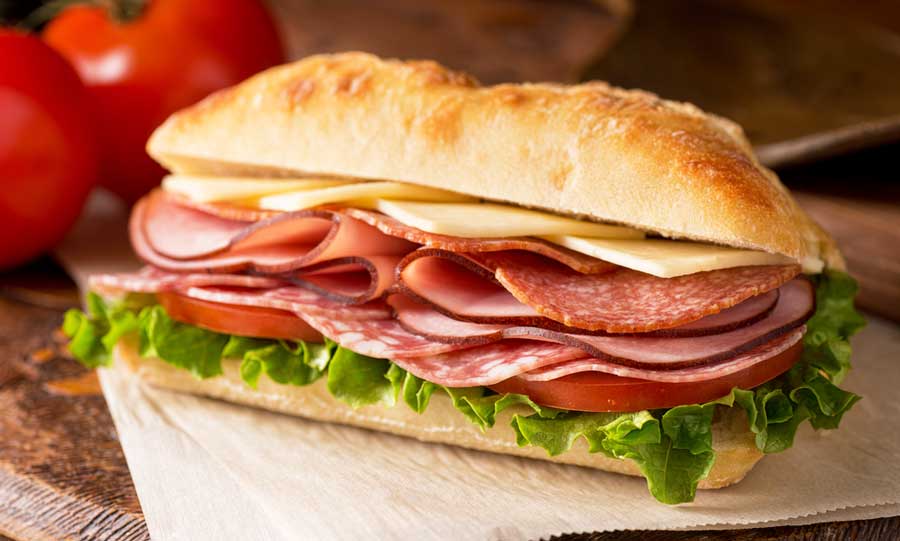 An Italian sandwich with meat, lettuce, tomatoes and cheese