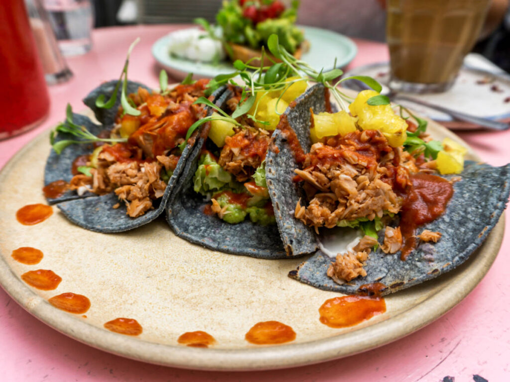 A plate of jackfruit tacos topped with avocado and pineapple