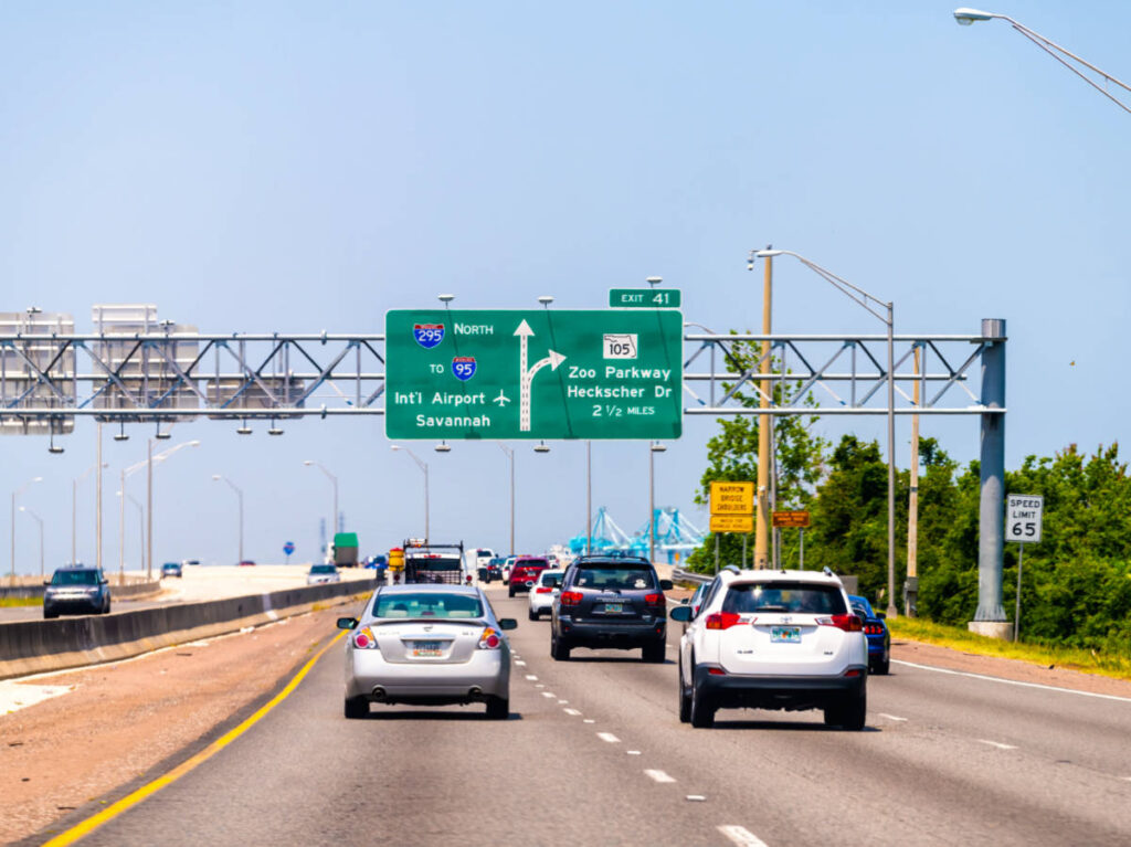 View of the cars driving along the highway with the road signs above