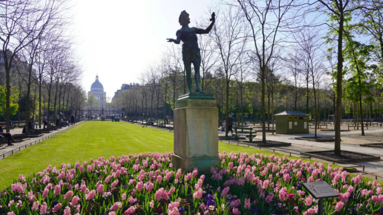 A statue surrounded by vibrant flowers in the Jardin du Luxembourg in Paris