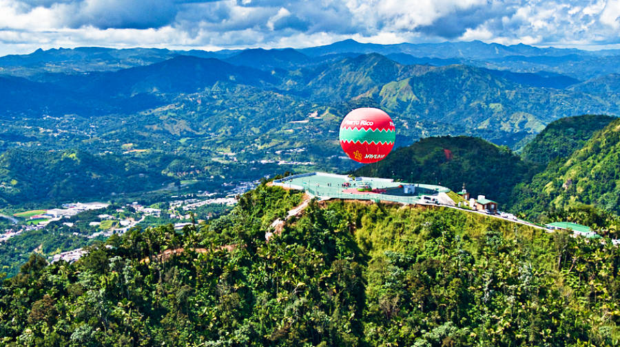 Aerial view of the beautiful landscape and a red and green aerostatic balloon of Jayuya