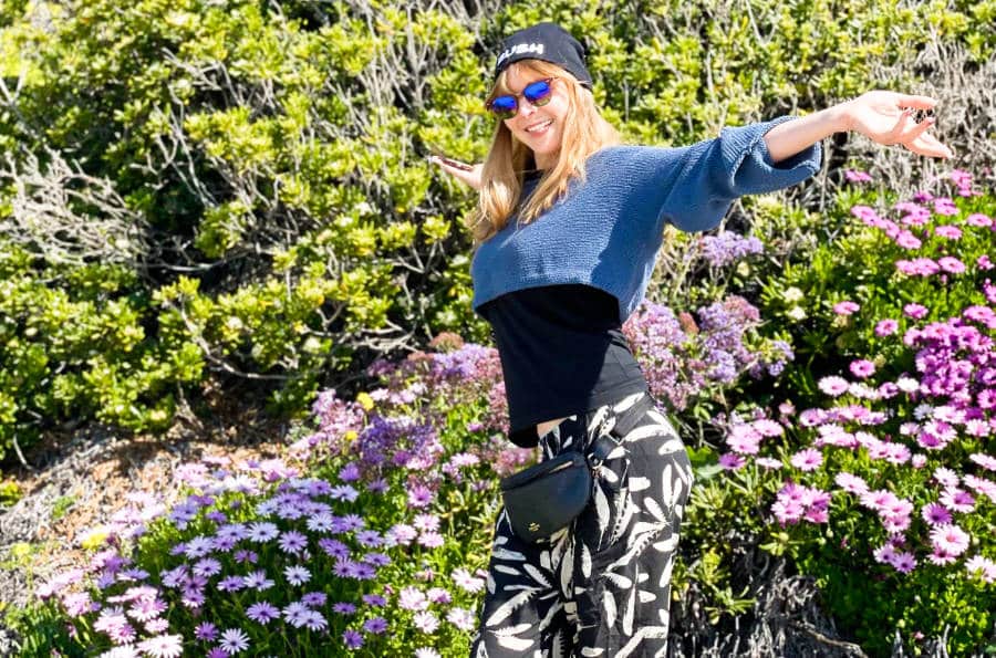 The author Jericha Griffin posing near the colorful flowers at Crystal Cove State Park