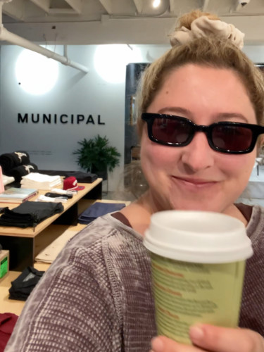 The author Jess Levy smiling for a photo while holding her Spanish latte from MUNICIPAL
