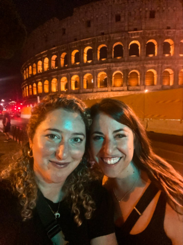 The author Jess and her friend posing for a photo in front of the Colosseum at night