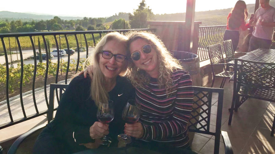 The author, Jess, and her mom posing while holding a glass of wine in Fazeli Cellars Winery at sunset