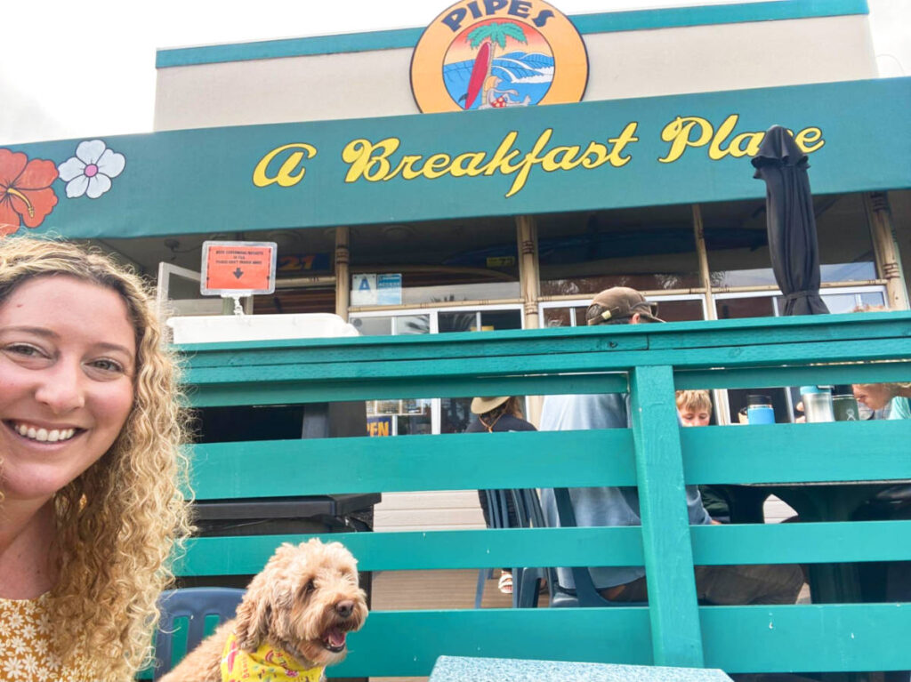 The author Jess Levy with her dog taking a photo in front of Pipes Cafe
