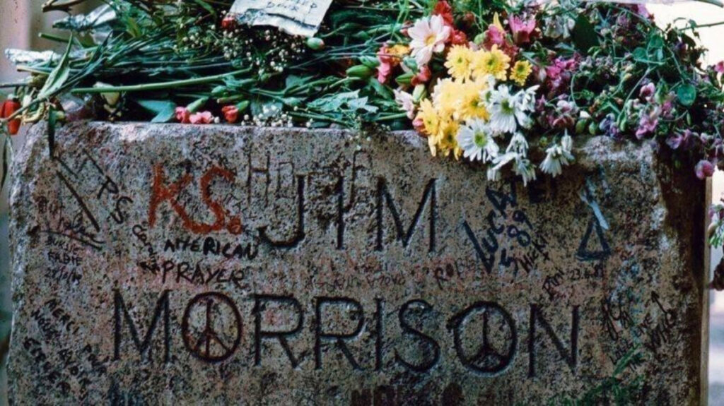 Vandalized grave of Jim Morrison with flowers on top at Père Lachaise cemetery