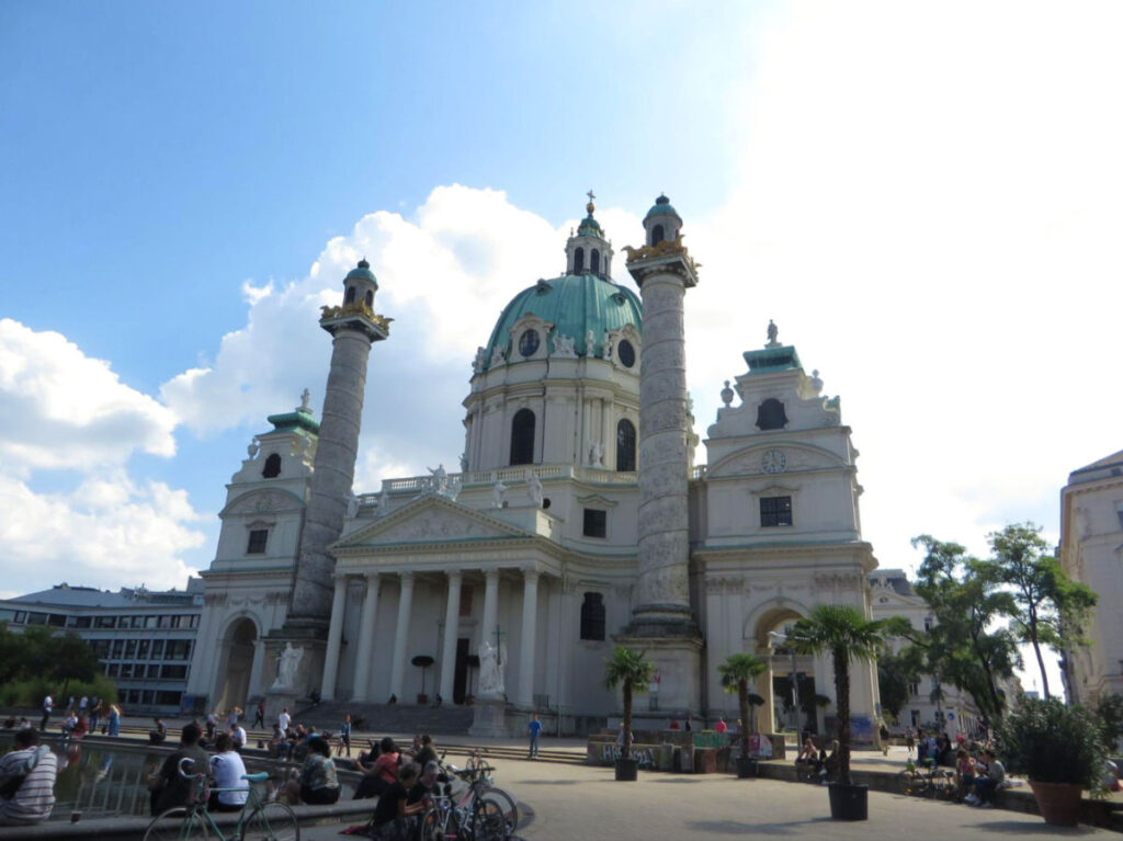Outside view of Karlskirche - a White church building with green domes in Vienna