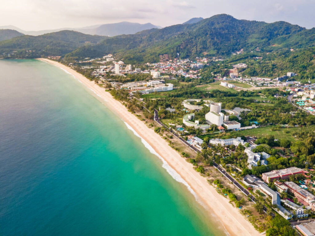 Aerial view of the long stretch Karon beach and the town surrounded by greenery