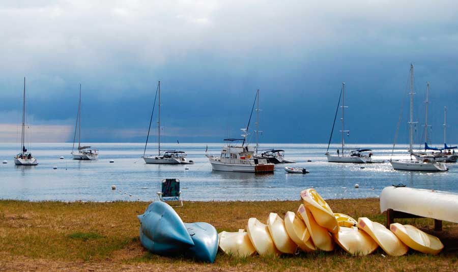 View of paddleboards on the sand and boats on the water
