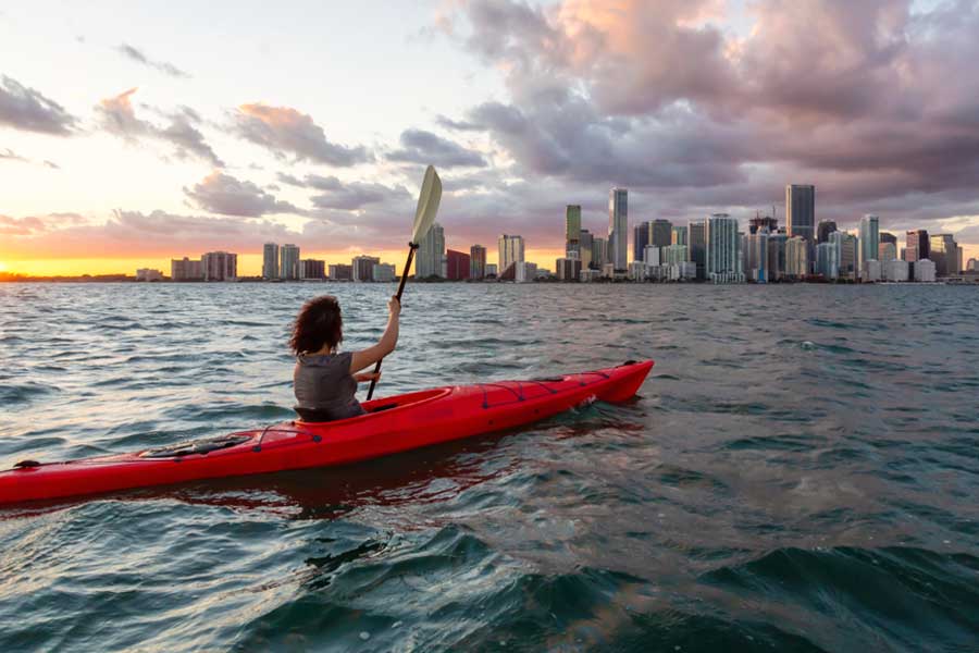 A woman kayaking in Miami with the view of skyscrapers from afar