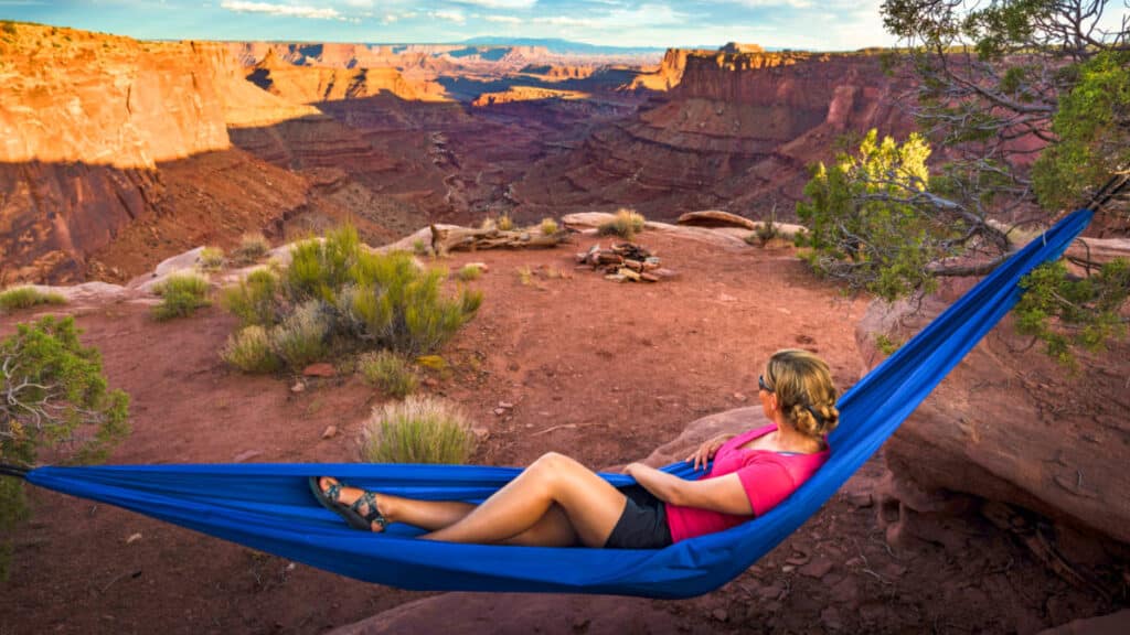 A woman on a blue hammock enjoying the view the majestic view at Kayenta Campground