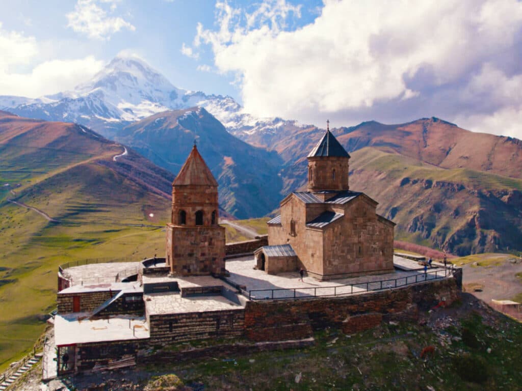 View of the Gergeti Trinity Church with the Kazbegi Mountain in the background on a sunny day