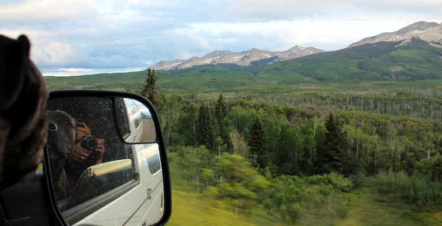 The author Abigail Nueve with her puppy taking a picture through the van's side mirror with a scenic view in Kebler Pass