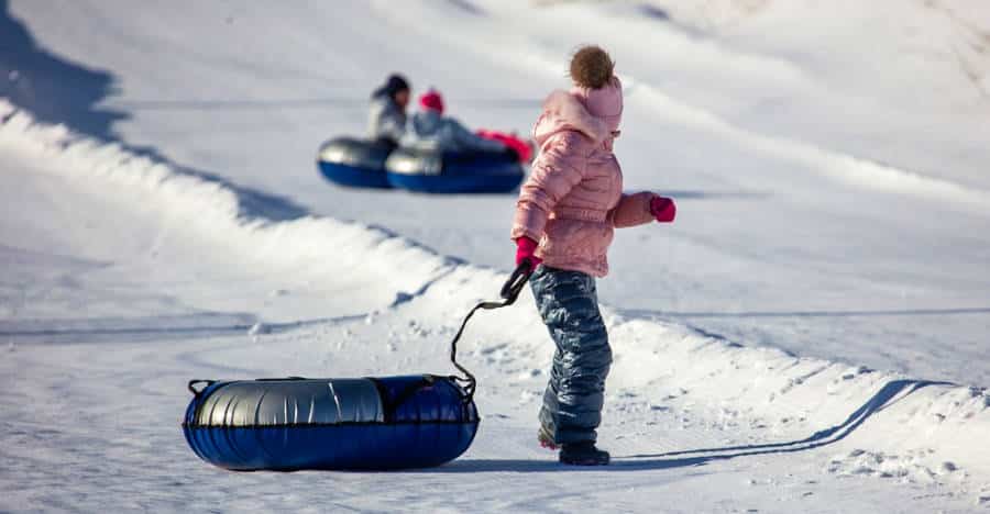 People snow tubing down a slope in winter