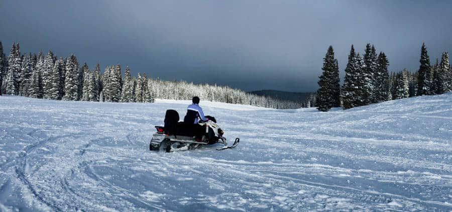 A man driving a snowmobile in the middle of Keystone Ski Resort