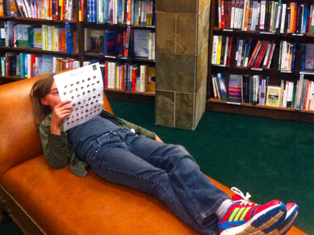 A child reading while lying on the couch inside the Tattered Cover