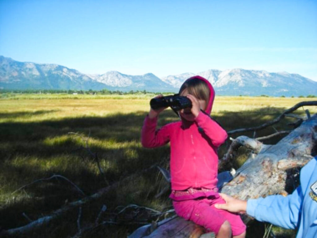 A kid looking at the Lake Tahoe with a binocular