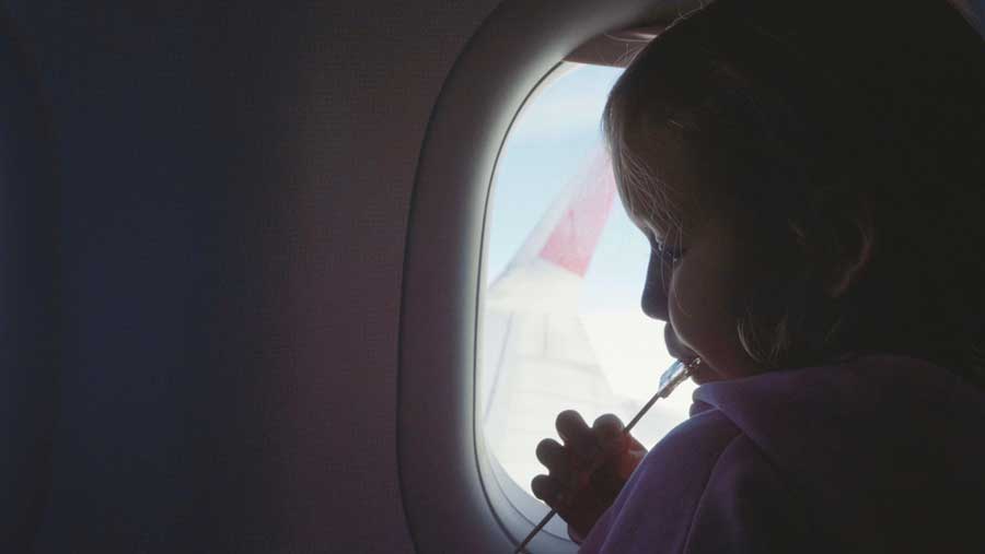 A little girl enjoying her lollipop while inside an airplane