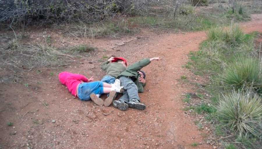 Kids laying down on the ground to take a break during a hike