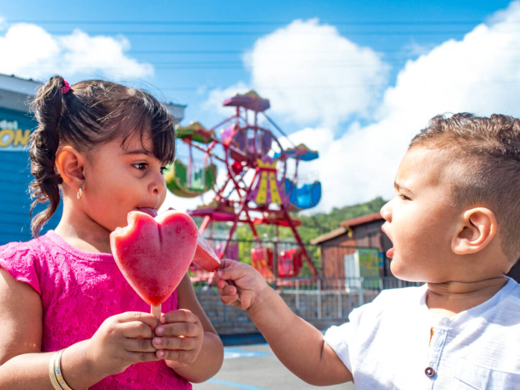 View of the two kids eating the heart-shaped popsicles at the park