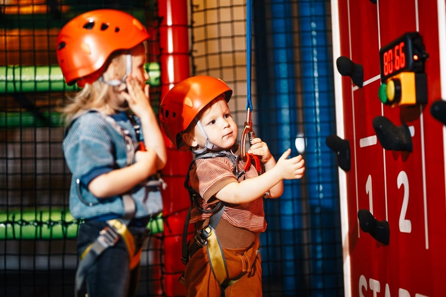 Two kids wearing helmets ready for an indoor bouldering