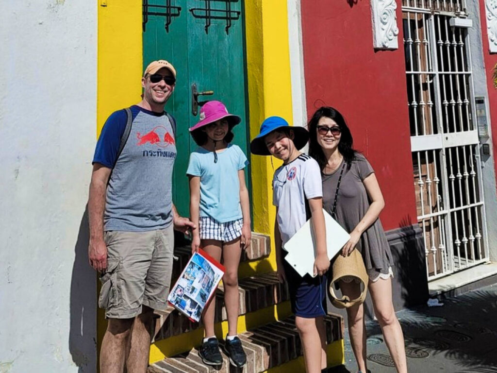 A family smiling for a photo on the colorful side of the street
