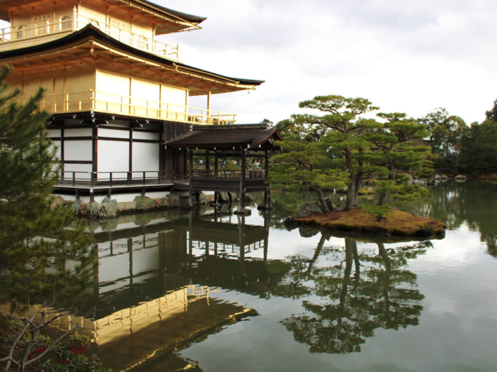 The golden Kinkakuji Temple surrounded by greenery reflecting on the water