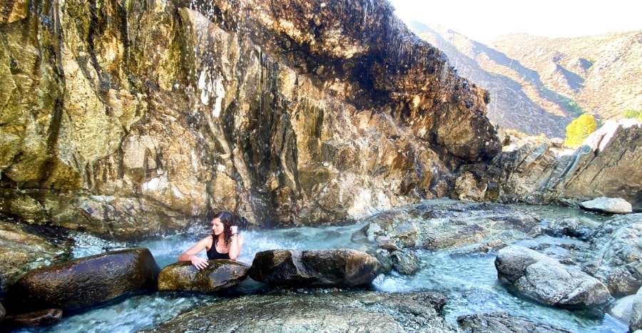 The author (Taylor Ramsey) soaking in the serene natural hot spring of Kirkham Hot Springs in Idaho, surrounded by brown rocks