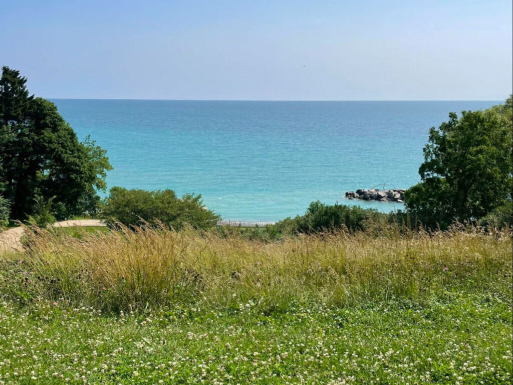 A grassy field at Klode Park in Whitefish Bay, offering a view of the ocean
