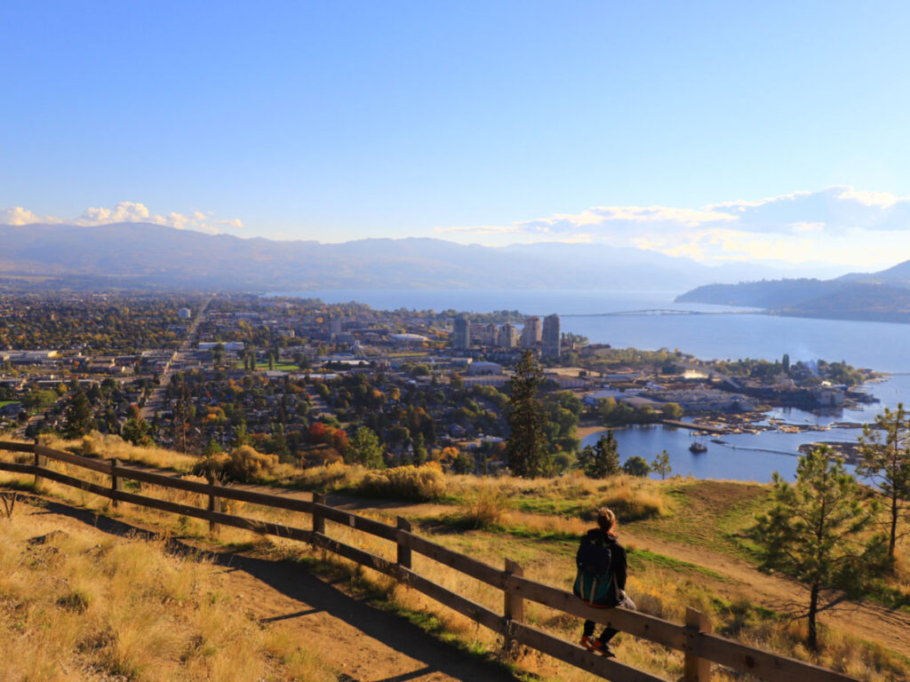 A person sitting in the wooden fence at Knox Mountain park in Kelowna