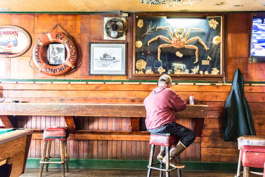 A man sitting at Kodiak’s B&B Bar with a displayed crab exoskeleton on the wall
