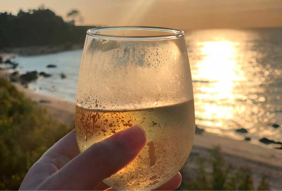 The author holding a glass of white wine from Kontokosta Winery during sunset
