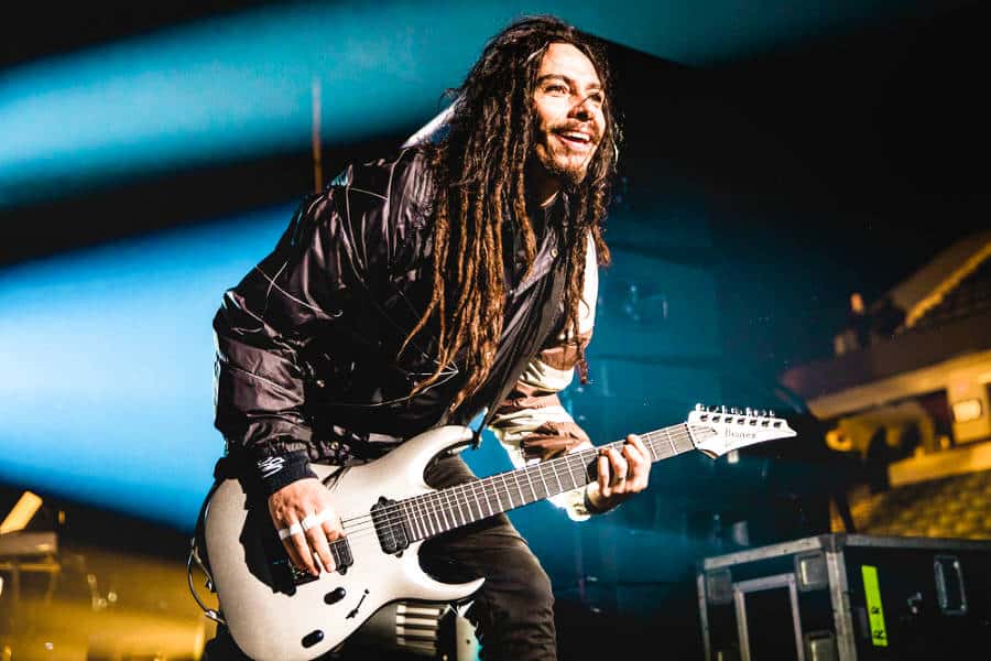 Korn smiling and playing the electric guitar on stage