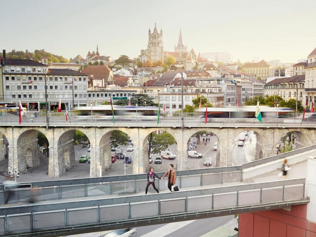 View of the people walking on the skywalk with the bridge and cityscape in the background