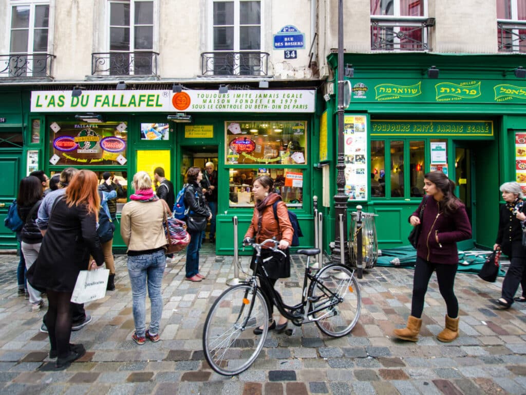 People passing by ang going inside the L’As du Fallafel
