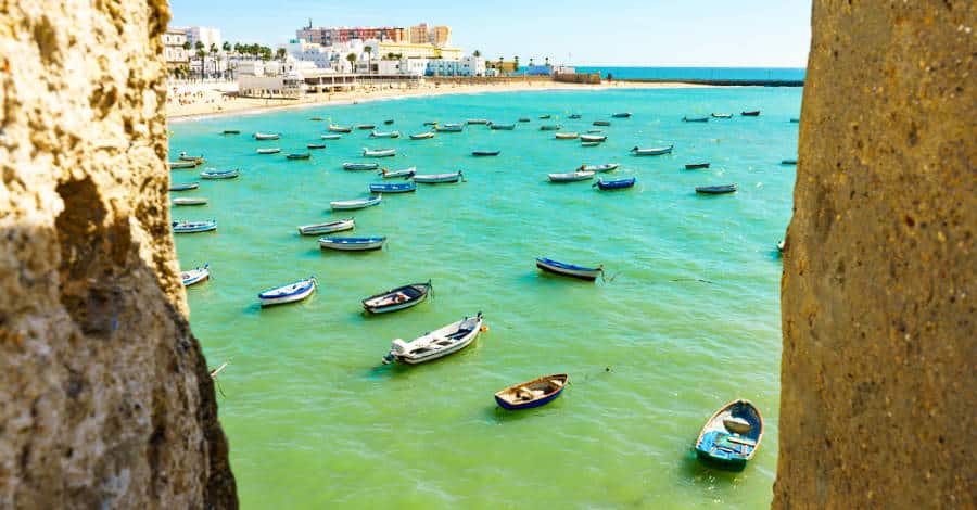 View in between of rock formations of boats sailing in La Caleta beach in Cadiz