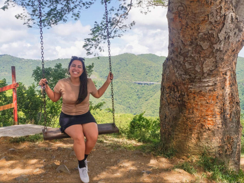 The author Vanessa Ramos smiling for a photo while on a swing in La Curva del Arbol