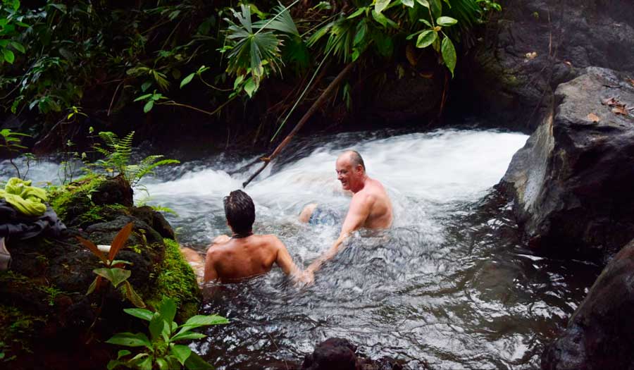 View of two man having fun in natural hot spring river in La Fortuna