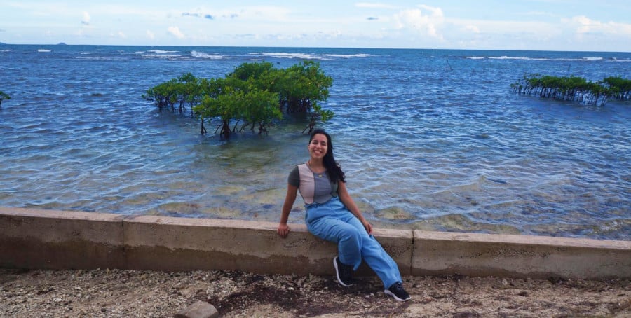 The author Vanessa Ramos sitting on a barrier at a local beach in Barrio Playa