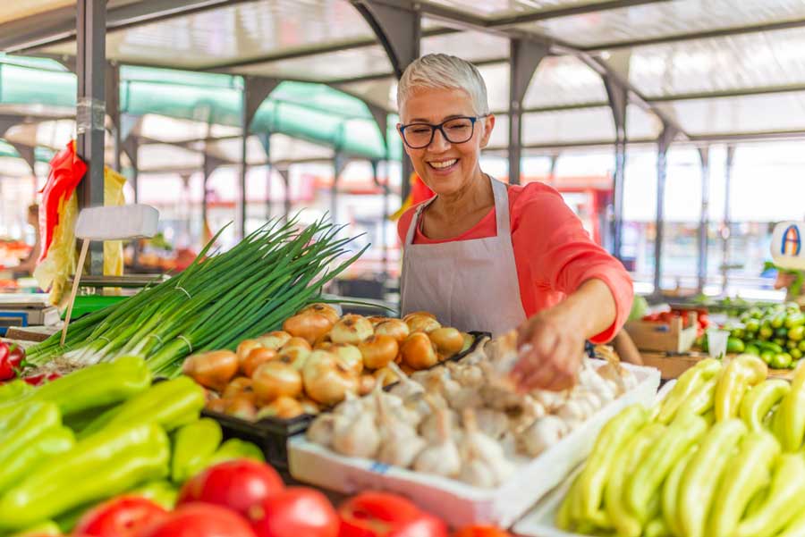 A woman picking fruits and vegetables in La Jolla Open Aire Farmers Market