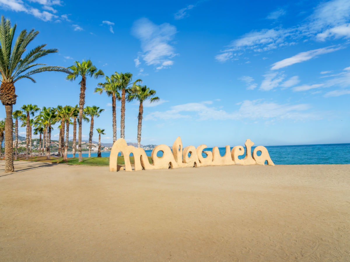 The Malagueta Sign with the blue beach with palm trees in the background