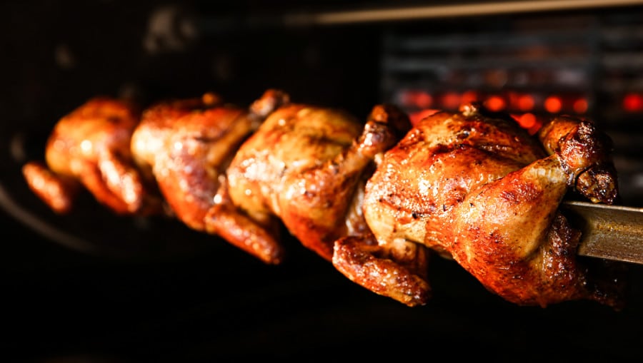 A close up look whole chickens grilled in rotisserie machine