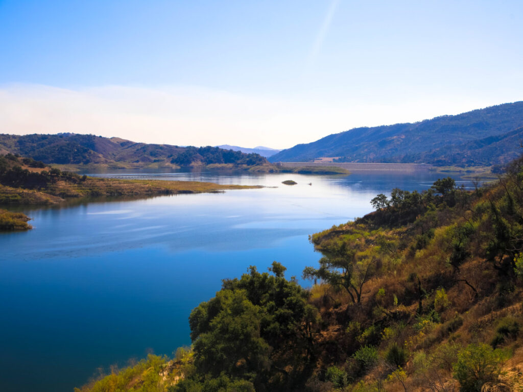 A serene lake nestled amidst lush hills and trees - Lake Casitas