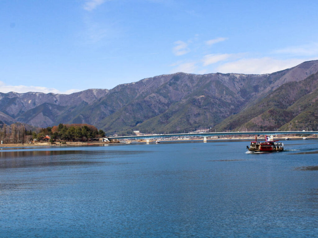 A boat sailing on the Lake Kawaguchi with mountain views