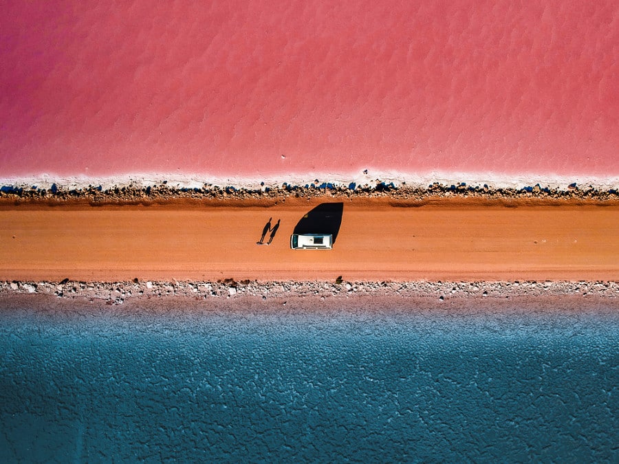 Aerial view of a camper van parked in the middle of the beautiful pink and blue lakes in Lake Macdonnell
