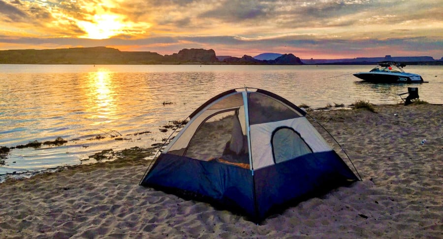 A tent near the water of Lake Powell during sunrise